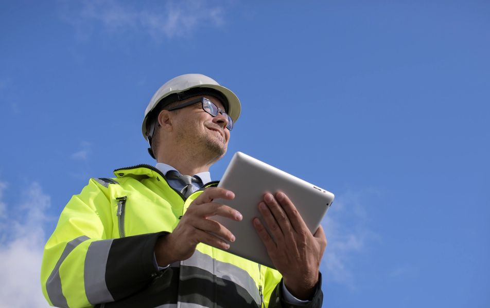 Construction engineer wearing safety vest against blue sky